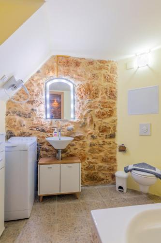 a bathroom with a sink and a stone wall at Thrapsano House with Private Pool for Families by Hospi Living in Heraklion