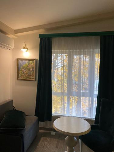 a living room with a table and a window at Fontush Boutique Hotel in Ivano-Frankivsʼk