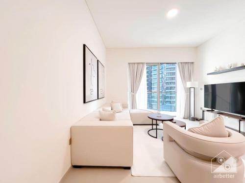 a white living room with a couch and a tv at Luxury & Elegance in Downtown Fountain Views in Dubai