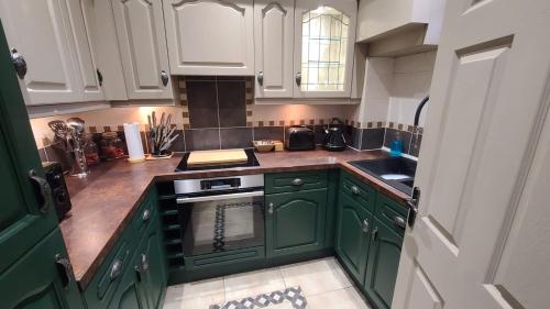 a kitchen with green cabinets and a stove top oven at Samuels' a duplex apartment by Spires Accommodation in Lichfield City Centre in Lichfield