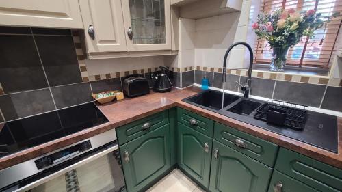 a kitchen with green cabinets and a sink at Samuels' a duplex apartment by Spires Accommodation in Lichfield City Centre in Lichfield