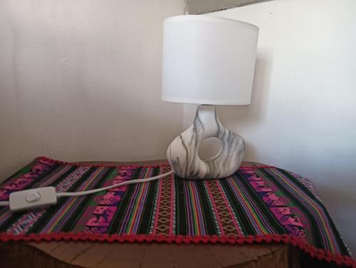 a lamp sitting on top of a table with a rug at Cabaña Nachitor in San Pedro de Atacama