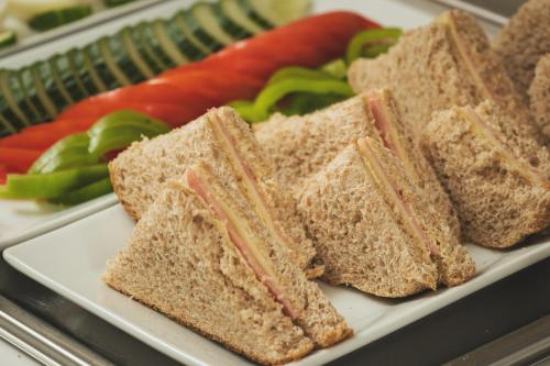 a sandwich cut in half on a plate with vegetables at Elia Palazzo Hotel in Chania Town