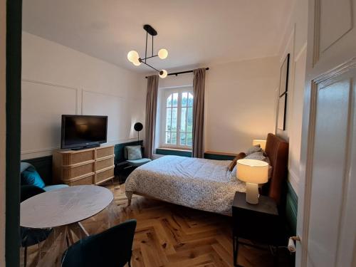 une chambre avec un lit, une télévision et une table dans l'établissement Résidence du Grand Hôtel à Châtel-Guyon, à Châtel-Guyon