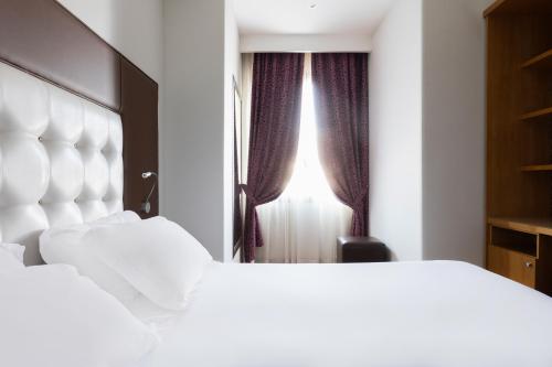 a bedroom with two white beds and a window at Hotel Royal Caserta in Caserta