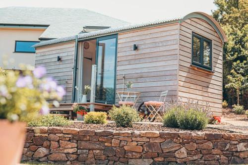 a small house with a stone wall at Elmhut Shepherd's Hut with Hot Tub in Minehead