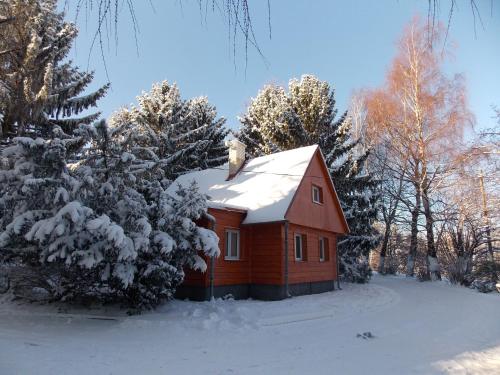 a small red house with snow on the roof at Srubová chata Oaza 1 in Trojanovice