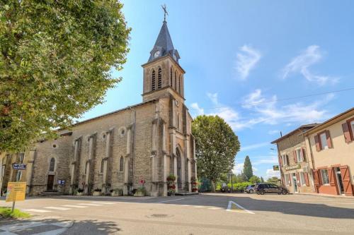 an old church with a clock tower on a street at Le Cologne - Les appartements de l'olivier in Loyettes