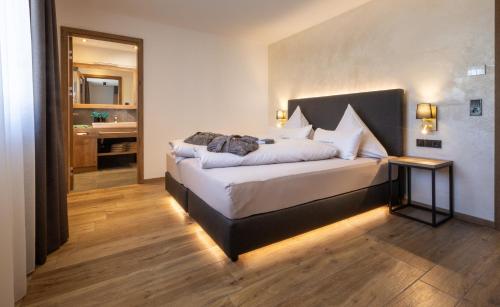 a bedroom with a large bed and a bathroom at FOR MOMENTS Apartments & Spa in Roßhaupten