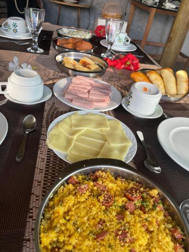 a table topped with a breakfast of eggs and ham at Pousada Porto de Paz - Noronha in Fernando de Noronha