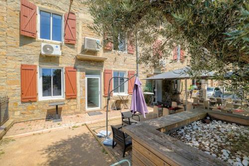 an outdoor patio with an umbrella and a building at Le Cologne - Les appartements de l'olivier in Loyettes