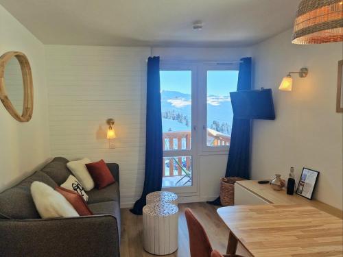 un salon avec un canapé, une table et une fenêtre dans l'établissement Le Croix Du Sud - 2050m La Plagne F2 Vue montagne, à La Plagne Tarentaise