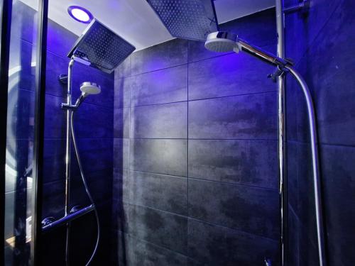 La salle de bains est pourvue d'une douche et d'un mur bleu. dans l'établissement La Cabane - Plagne Village, F2 Ski aux pieds, à La Plagne Tarentaise