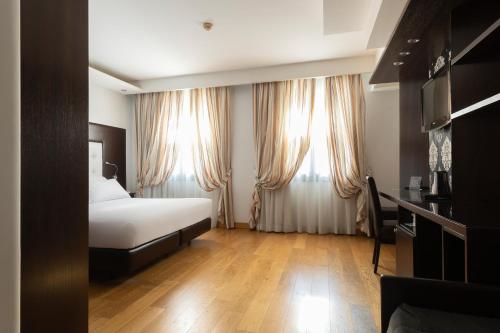 a hotel room with a bed and two windows at Hotel Royal Caserta in Caserta
