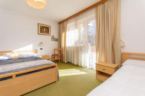 Un dormitorio con dos camas y una ventana. en Appartamento Alessandra 106, en Vigo di Fassa