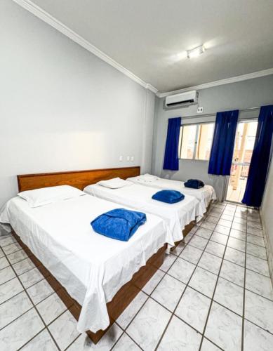 two beds in a room with blue curtains at Hotel Grande Serra in Trindade