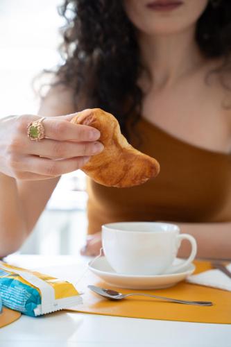 a woman holding a piece of bread next to a cup of coffee at Afrodite Guest House in Caserta