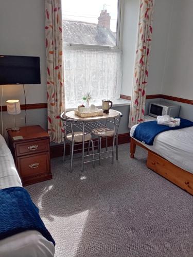 a room with two beds and a table and a window at sark guest house in Barnstaple