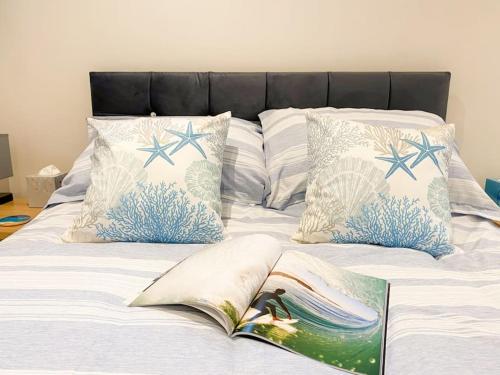 a bed with pillows and an open book on it at Cosy Coastal Getaway in West Wittering