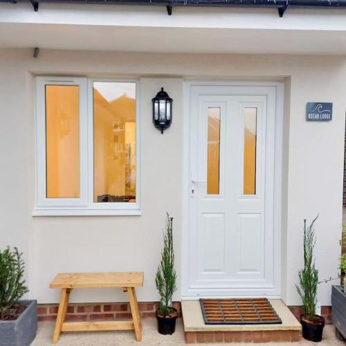 a front door of a house with a bench and a lamp at Cosy Coastal Getaway in West Wittering