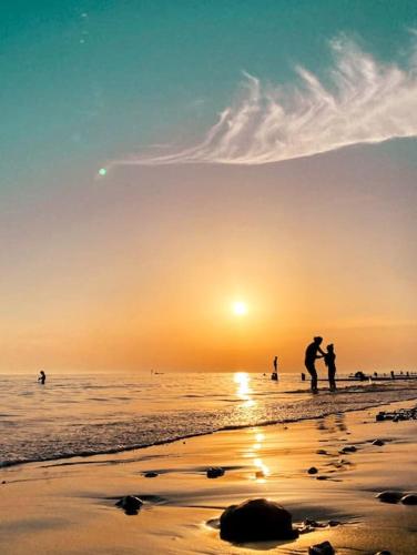 a group of people standing on the beach at sunset at Cosy Coastal Getaway in West Wittering