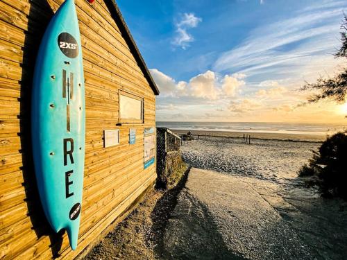 a surfboard on the side of a building on the beach at Cosy Coastal Getaway in West Wittering