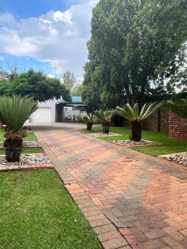 a brick driveway with palm trees in a yard at B3 Self-catering accommodation Potch in Potchefstroom