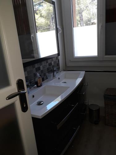 La salle de bains est pourvue d'un lavabo blanc et de 2 fenêtres. dans l'établissement Blue note, à Cassis