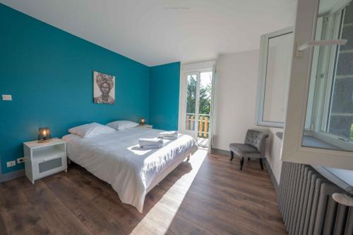 a bedroom with a large bed and a blue wall at La Villa du Pont Romain in Saint-Nectaire