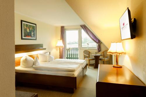 a hotel room with a bed and a window at Eisenberger Hof in Moritzburg