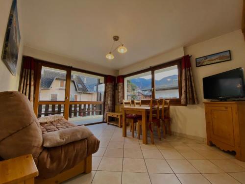 un salon avec un canapé et une table avec une télévision dans l'établissement Charmant T2 au cœur de Samoëns avec balcon, proche commerces et ski-bus - FR-1-624-44, à Samoëns