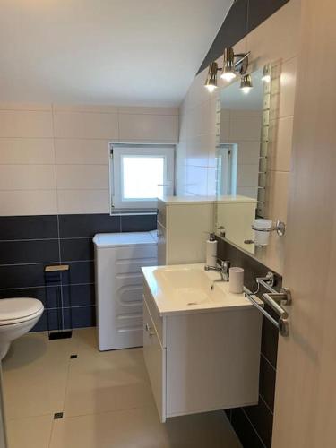 a bathroom with a sink and a toilet and a mirror at Grey Beach Apartment in Stara Novalja