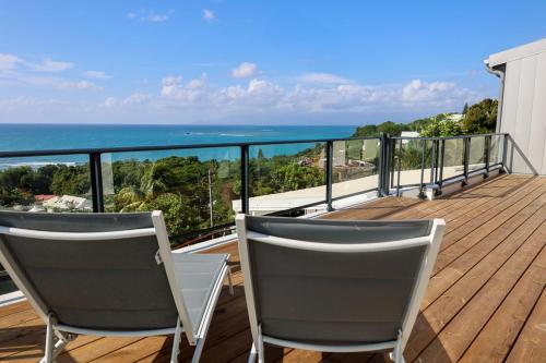 two chairs sitting on a deck with a view of the ocean at Villa Constellation vue Mer piscine et plage à pied in Le Gosier