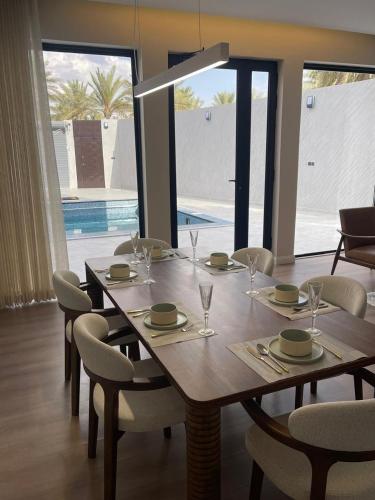 a wooden table with chairs and a dining room with a pool at لوقانو فيلا Lugano Villa in Hail