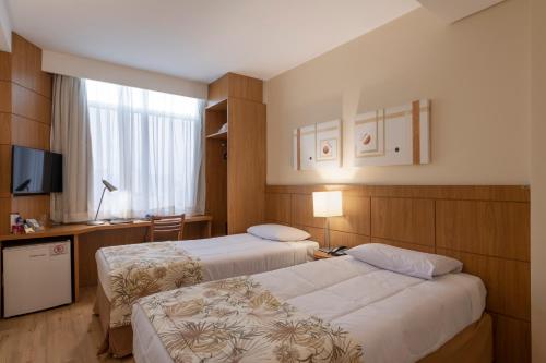 a hotel room with two beds and a television at Monreale Plus São José dos Campos in São José dos Campos