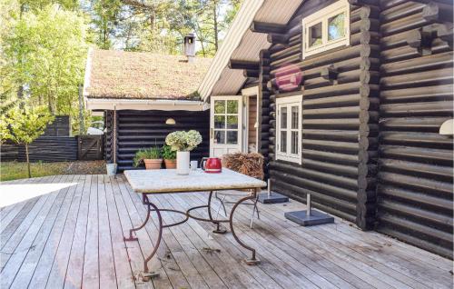 a wooden deck with a table in front of a log cabin at 4 Bedroom Awesome Home In Hornbæk in Hornbæk