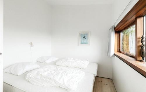 a white bed in a white room with a window at Holiday Home Klinteløkken Allinge V in Allinge