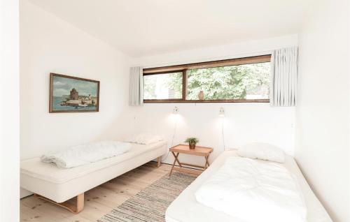 a white room with two beds and a window at Holiday Home Klinteløkken Allinge V in Allinge