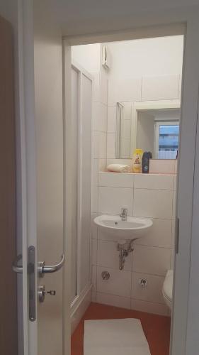 a white bathroom with a sink and a mirror at Gästepension - Elsterland am Sport- und Freizeitpark in Elster