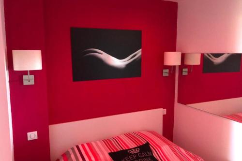 - une chambre rouge avec un lit et deux lampes dans l'établissement Naturiste Cap d'Agde Port Nature 854, au Cap d'Agde