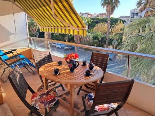 une table et des chaises en bois sur un balcon dans l'établissement Bel appart centre Lavandou, clim, Wi-Fi, proche plage - FR-1-308-185, au Lavandou