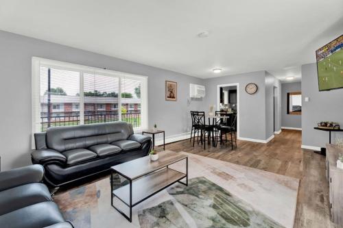 a living room with a black leather couch and a table at Central Home and Serene WiFi Pet Friendly in Sterling Heights