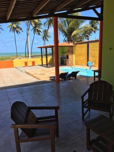 a patio with chairs and a pool and palm trees at Casa da Santa in Coruripe