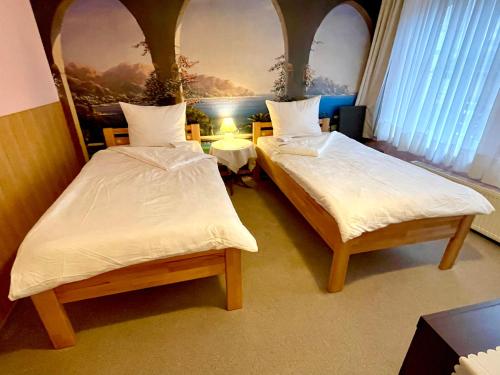 two beds in a room with two tables and a painting at Just Pension & Bar in Gadebusch