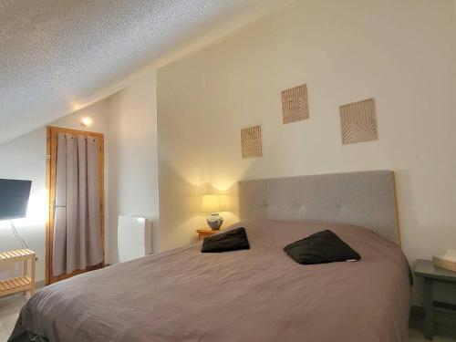 une chambre avec un grand lit avec deux oreillers dessus dans l'établissement Duplex 6 pers - Centre station - Ski/Randonnées - Balcon - FR-1-393-177, à Saint-Michel-de-Chaillol