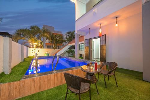 a patio with a table and chairs next to a swimming pool at ll EMPYREAN STAY II LUXURY ll CELESTIAL UNICORN VILLA ll 3BHK ll AC ll PRIVATE BIG POOL ll in Lonavala