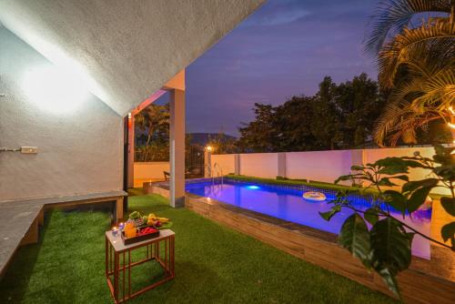 a house with a swimming pool at night at ll EMPYREAN STAY II LUXURY ll CELESTIAL UNICORN VILLA ll 3BHK ll AC ll PRIVATE BIG POOL ll in Lonavala