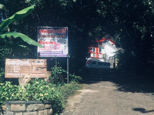 a sign in front of a road with a house at Koslanda Rest & Homestay in Koslanda