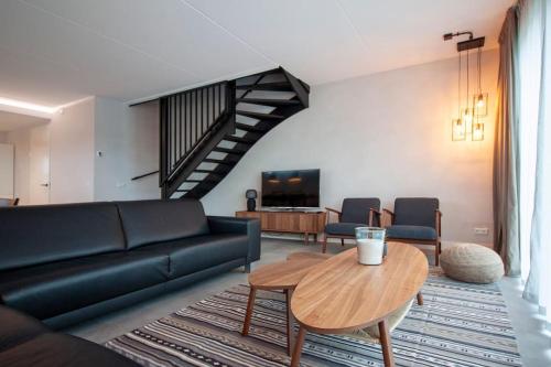 a living room with a black couch and a table at Wonderful Villa on water with 5 bedrooms and bathrooms in Stavoren