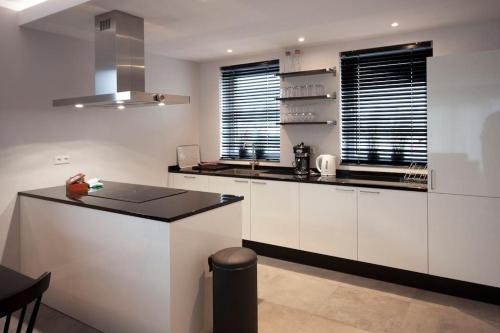 a kitchen with white cabinets and a black counter top at Wonderful Villa on water with 5 bedrooms and bathrooms in Stavoren